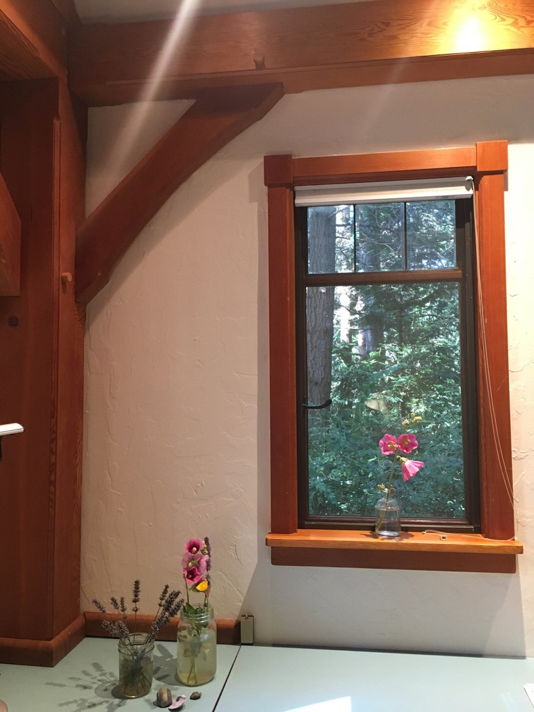 flowers, light, and wooden-framed window and wood beams in a stuccoed room