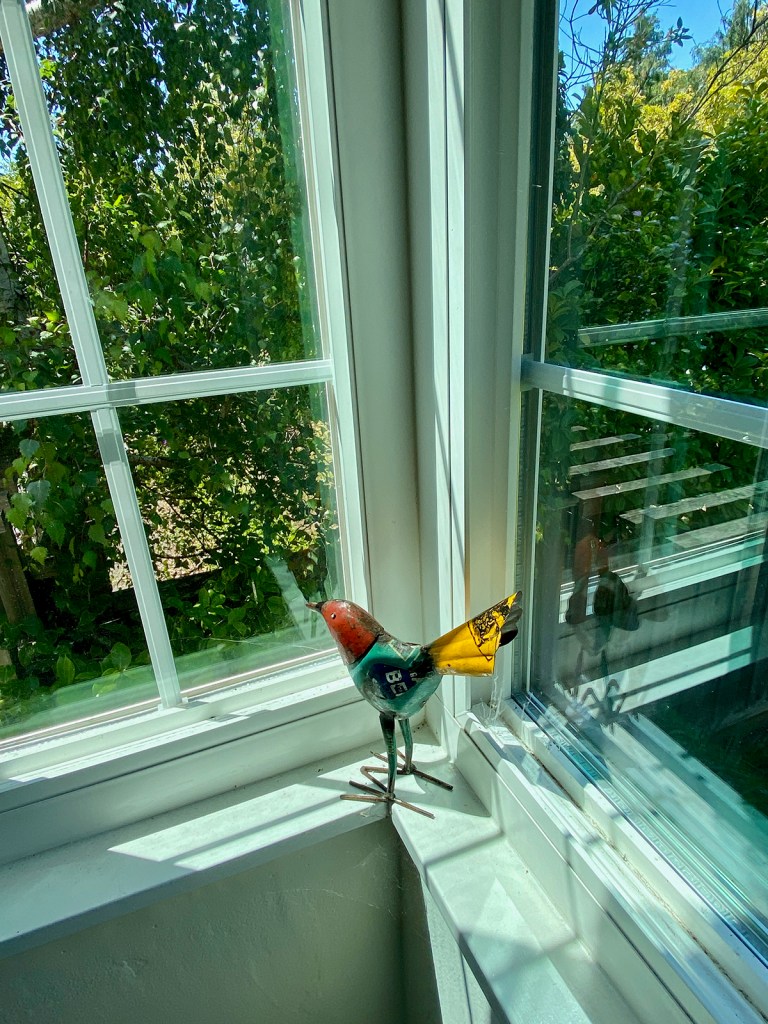 Metal bird multicolored looking out window